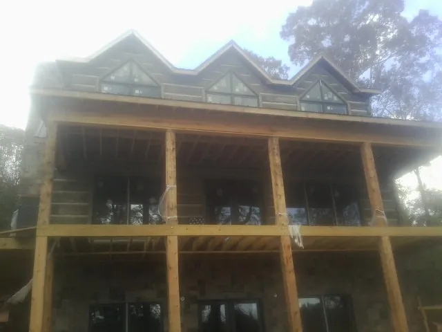 Dormers and porch framing on a large log home under construction — Roof Coating work by our crew in Clare